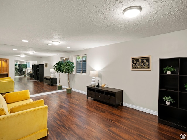 living area with baseboards, wood finished floors, and a textured ceiling