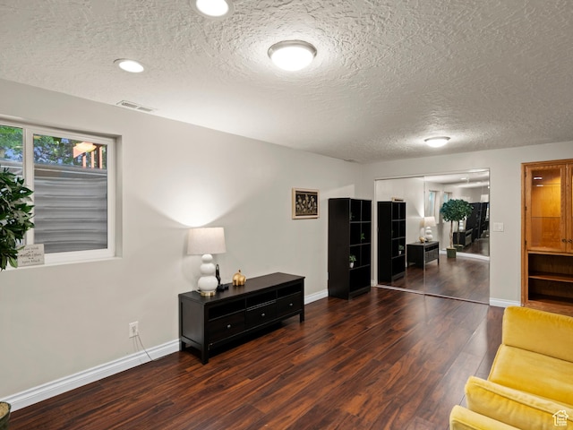 sitting room with baseboards, wood finished floors, visible vents, and a textured ceiling