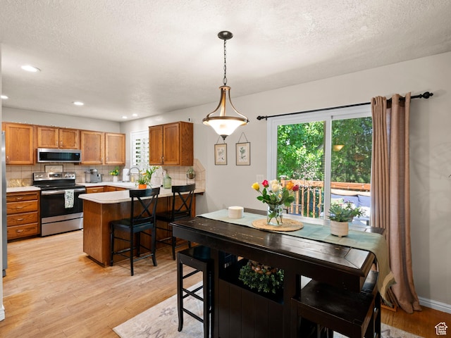 dining area featuring light wood-style flooring, a textured ceiling, and a healthy amount of sunlight