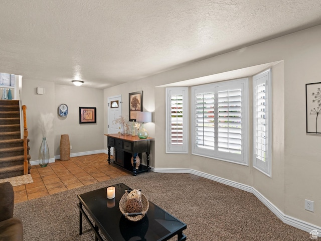 living area with stairs, tile patterned flooring, a textured ceiling, and plenty of natural light