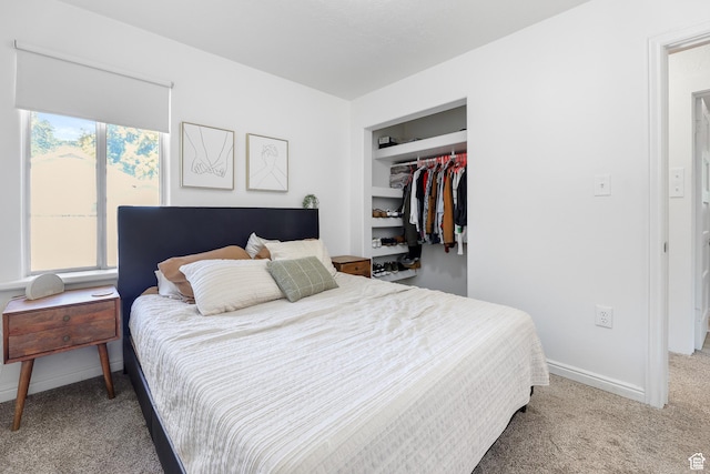 carpeted bedroom with a walk in closet, a closet, and baseboards