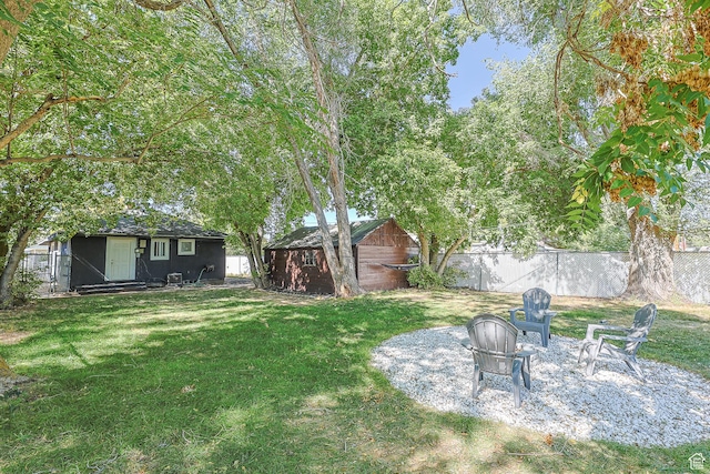 view of yard with a fire pit, an outdoor structure, and fence
