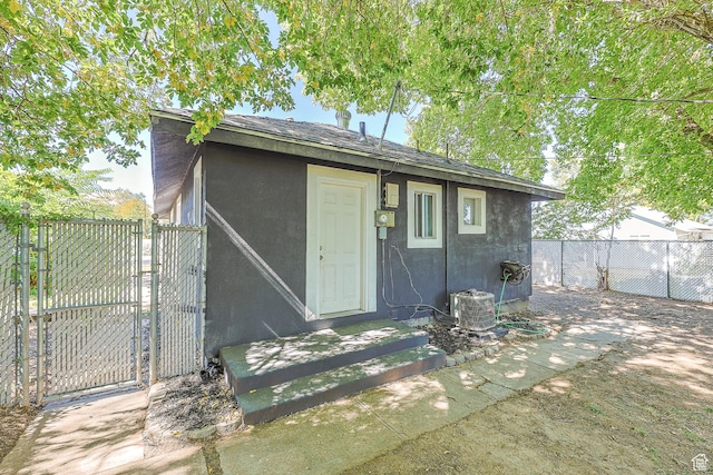 view of outbuilding featuring a gate, central AC, and fence