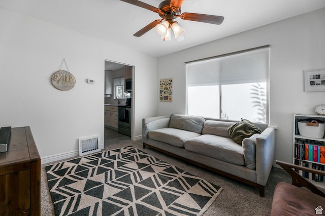 carpeted living area with baseboards, a ceiling fan, visible vents, and a sink