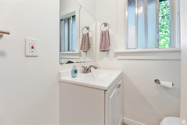 bathroom with baseboards, vanity, and toilet