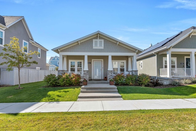 craftsman-style house with fence, a front lawn, covered porch, and stucco siding