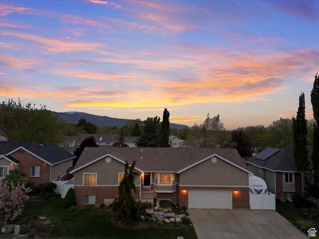 view of front of home featuring driveway, a residential view, a mountain view, an attached garage, and fence