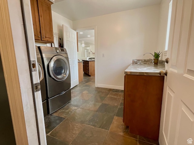 laundry room with washer and dryer, cabinet space, stone finish flooring, a sink, and baseboards