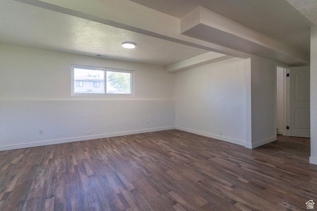 empty room with a textured ceiling, dark wood-style floors, and baseboards