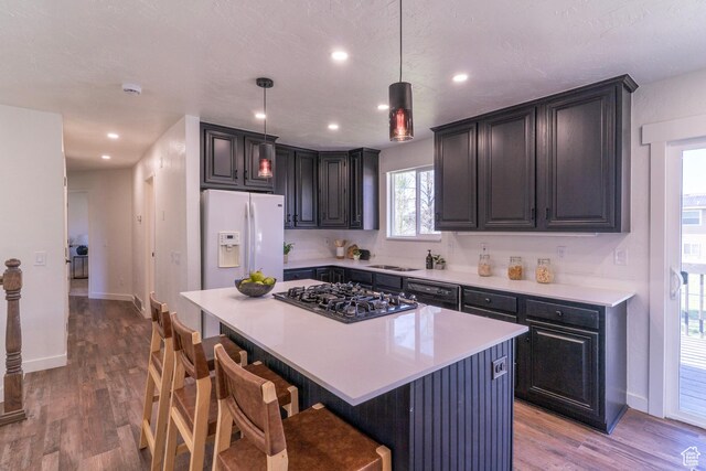 kitchen with black appliances, a breakfast bar, wood finished floors, and light countertops