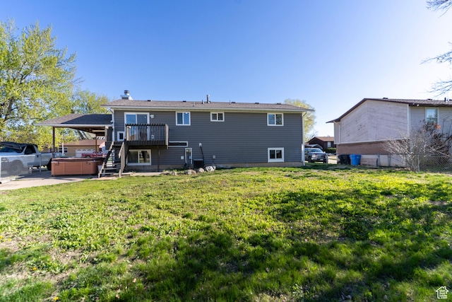 back of property with a deck, a hot tub, fence, stairway, and a yard