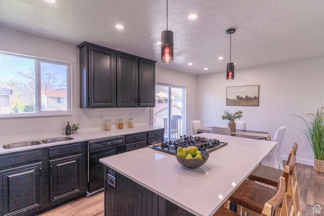 kitchen featuring recessed lighting, black appliances, light wood-style floors, and a sink