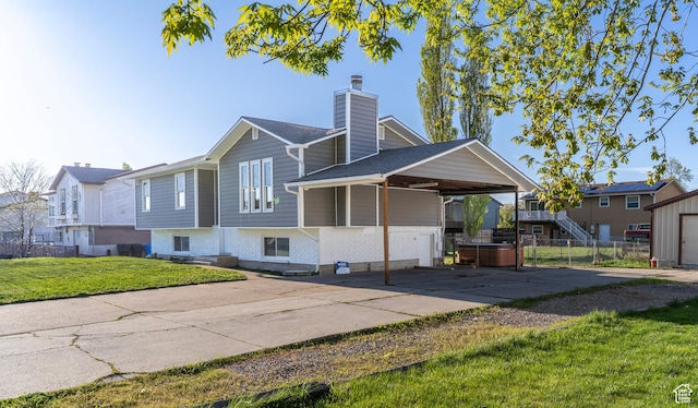 view of front of house with a chimney, fence, a hot tub, an attached carport, and a front yard