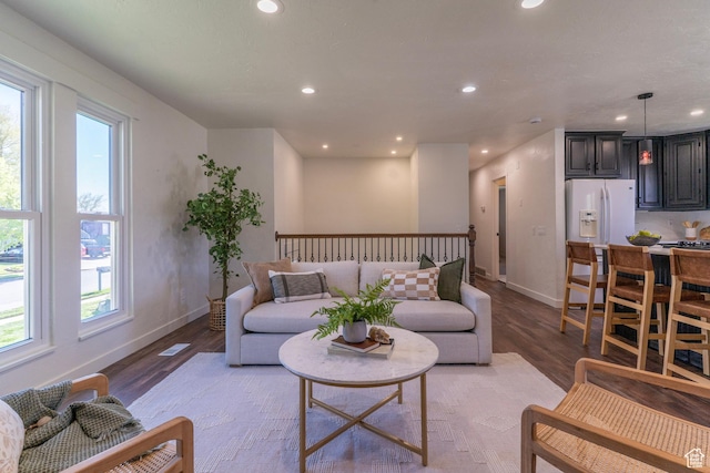 living area with baseboards, light wood-type flooring, a healthy amount of sunlight, and recessed lighting