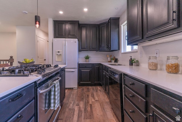 kitchen featuring white fridge with ice dispenser, light countertops, stainless steel gas stove, dark wood-style flooring, and dishwasher