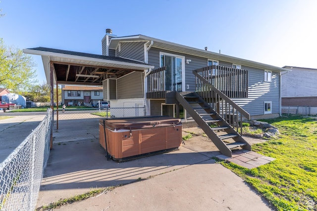 rear view of house featuring stairway, a patio area, a hot tub, a carport, and a chimney