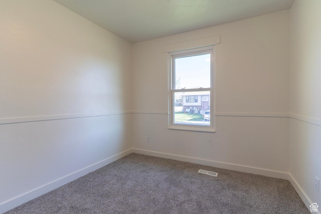 carpeted spare room featuring visible vents and baseboards
