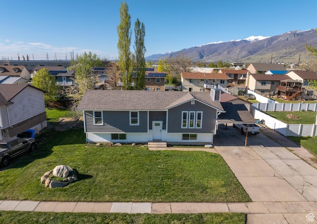 view of front of home featuring fence, a residential view, driveway, a mountain view, and a front lawn