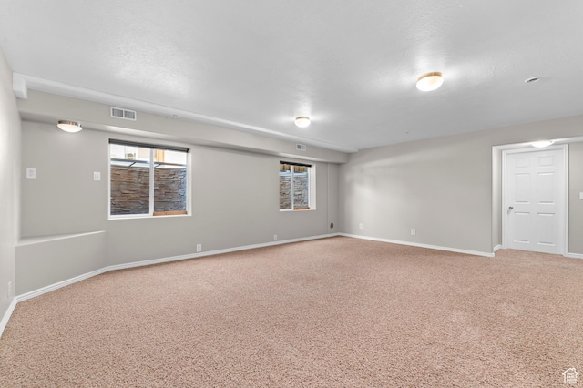 empty room with carpet floors, visible vents, and baseboards
