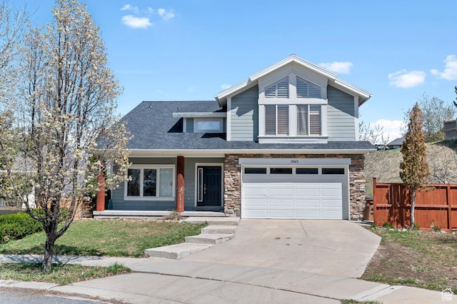 view of front of property with an attached garage, driveway, stone siding, and fence