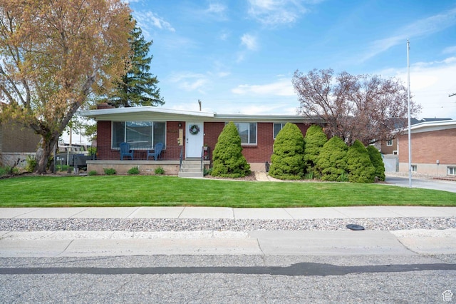 view of front of property with brick siding, a front lawn, and covered porch