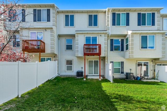 back of property featuring stucco siding, fence, central air condition unit, and a lawn