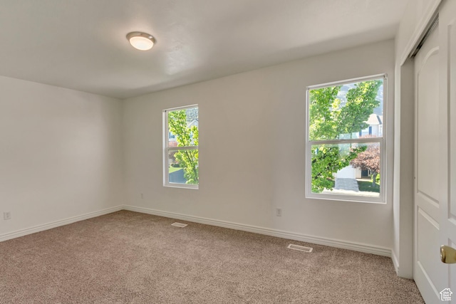 spare room with baseboards, carpet flooring, and visible vents