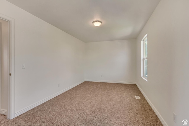 unfurnished room with light carpet, visible vents, and baseboards