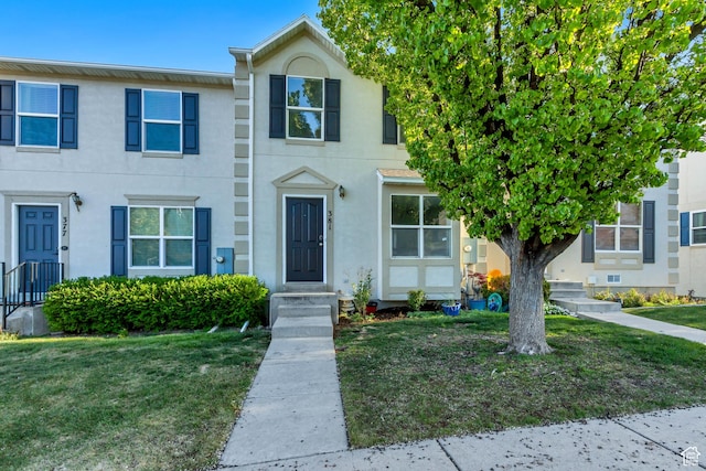 multi unit property with a front lawn and stucco siding