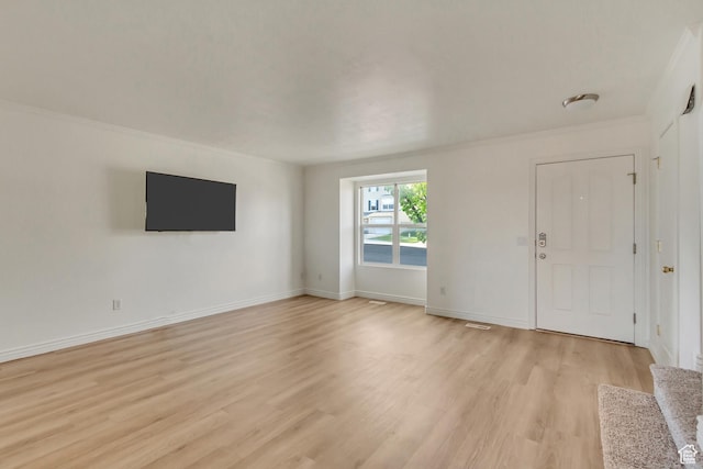 unfurnished living room with light wood finished floors, baseboards, and crown molding