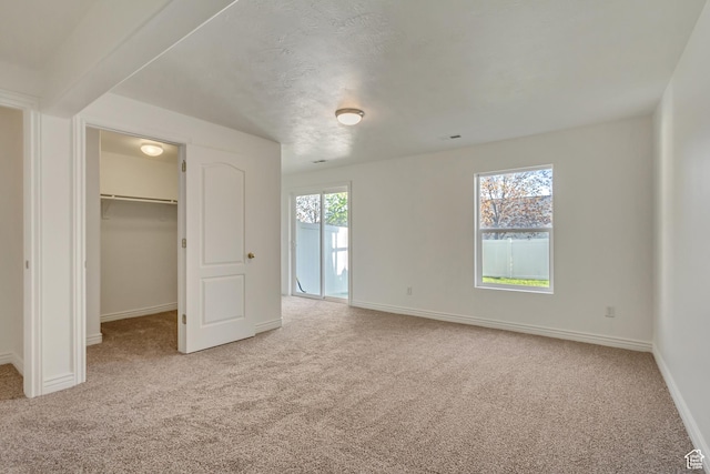 unfurnished bedroom with baseboards, carpet, and a walk in closet
