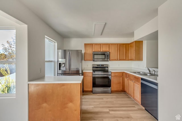 kitchen featuring light countertops, light wood finished floors, stainless steel appliances, and a sink