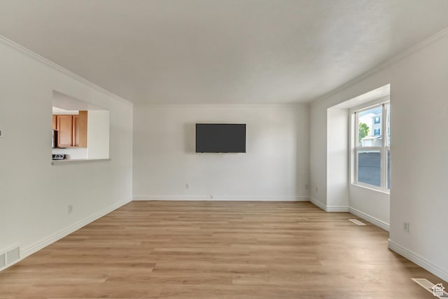 unfurnished living room featuring light wood-style floors, visible vents, crown molding, and baseboards