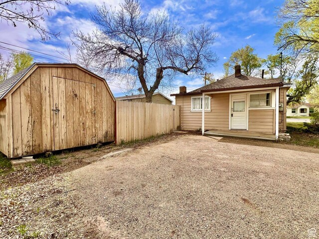152 N 400 E, Vernal, UT 84078 - rear view of property featuring a storage shed, an outbuilding, roof with shingles, a chimney, and fence