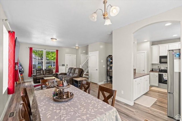 1521 W Kinloch Way, West Valley City, UT 84119 - dining room with light wood finished floors, visible vents, arched walkways, baseboards, and stairs