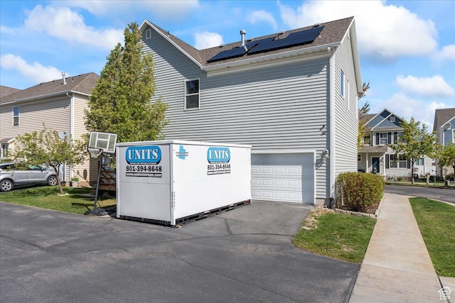 1521 W Kinloch Way, West Valley City, UT 84119 - view of property exterior featuring roof mounted solar panels, an attached garage, and aphalt driveway