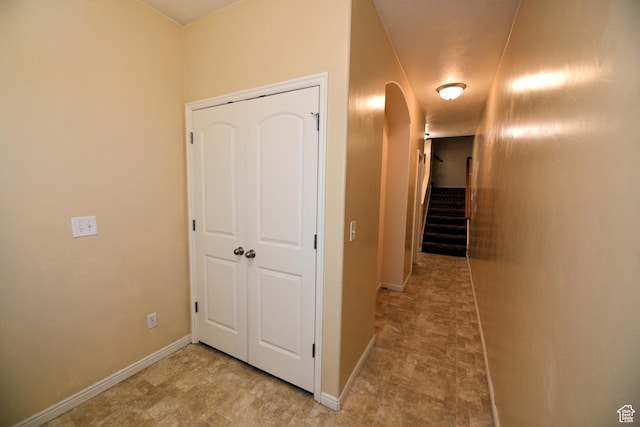 hall featuring baseboards, arched walkways, and stairway