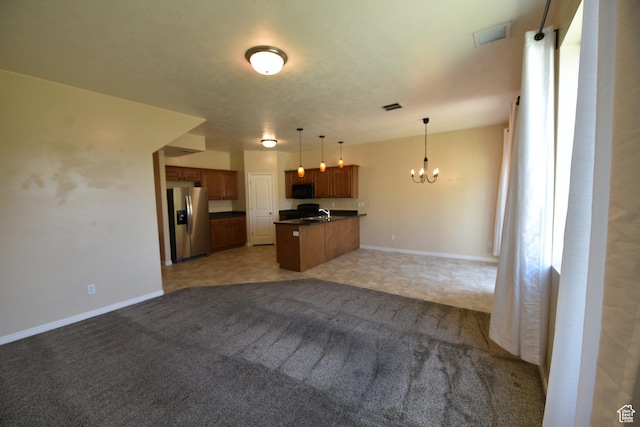 kitchen with open floor plan, dark countertops, a chandelier, brown cabinets, and stainless steel refrigerator with ice dispenser