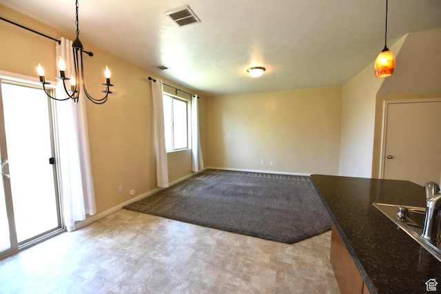 unfurnished dining area featuring a sink, baseboards, visible vents, a chandelier, and light colored carpet