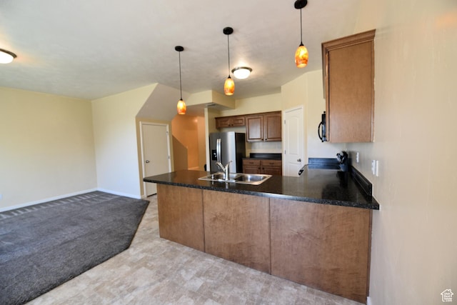 kitchen featuring a peninsula, light carpet, a sink, stainless steel fridge, and pendant lighting