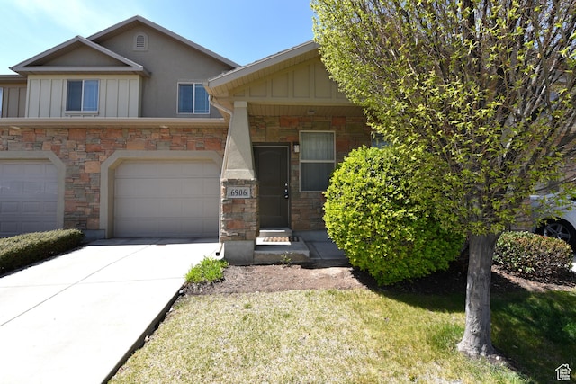 view of front of house featuring board and batten siding, driveway, stone siding, and a garage
