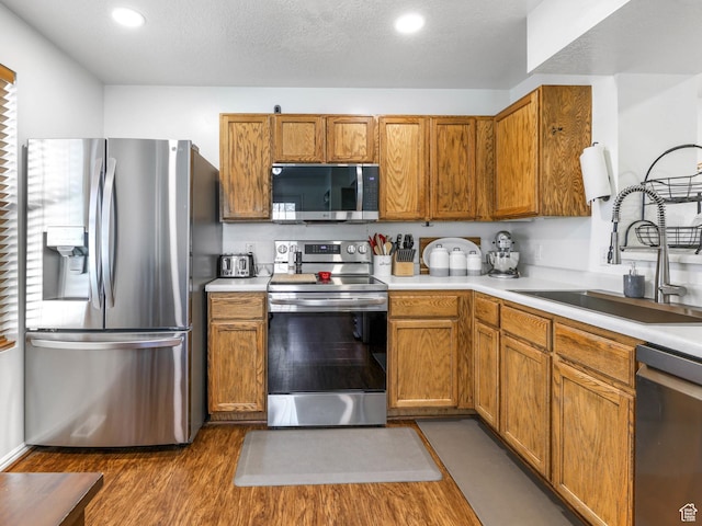 734 N 170 W, Tooele, UT 84074 - kitchen featuring stainless steel appliances, light countertops, wood finished floors, a sink, and brown cabinetry