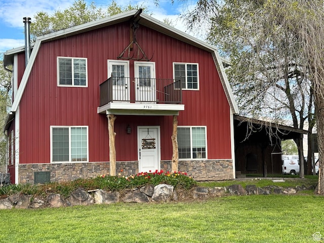 view of front facade featuring stone siding, a front lawn, and a balcony