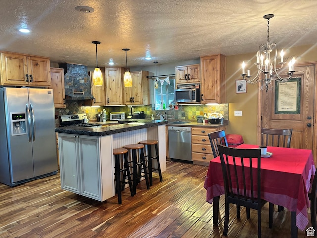 9762 S 3350 W, Payson, UT 84651 - kitchen with wall chimney range hood, stainless steel appliances, dark wood finished floors, a notable chandelier, and a kitchen island