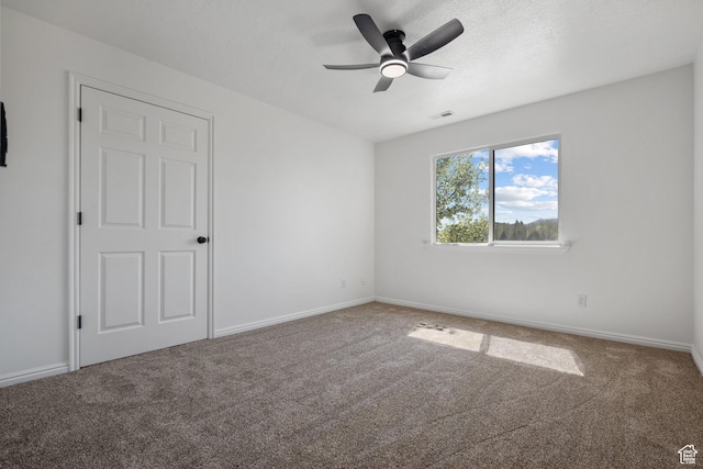 unfurnished room with visible vents, carpet flooring, baseboards, and a ceiling fan