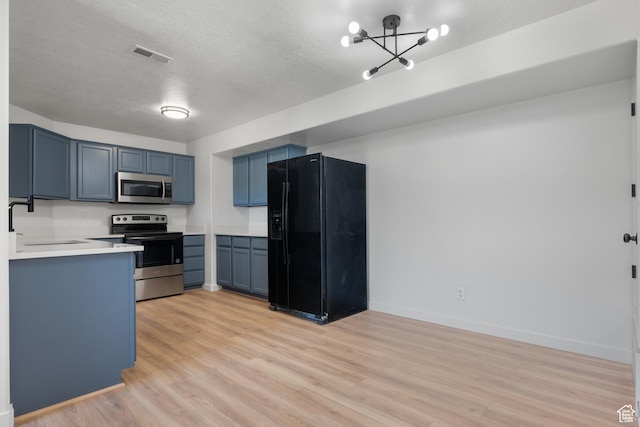 kitchen with stainless steel appliances, a sink, light wood-style floors, blue cabinetry, and light countertops
