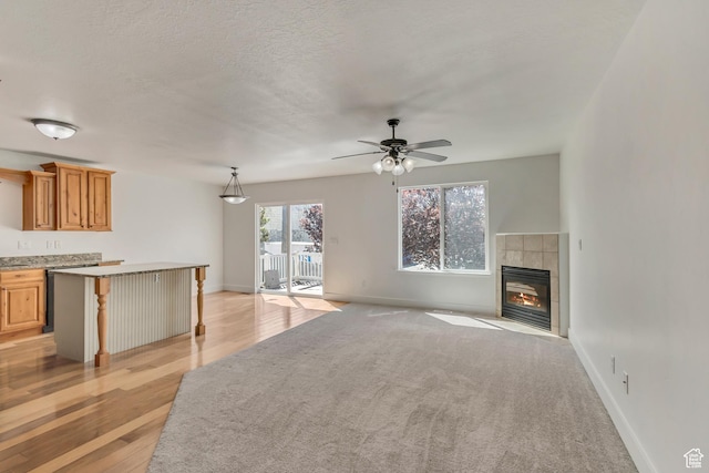 2074 S Orchard Dr, Bountiful, UT 84010 - unfurnished living room featuring a tile fireplace, a ceiling fan, light wood-type flooring, baseboards, and light colored carpet