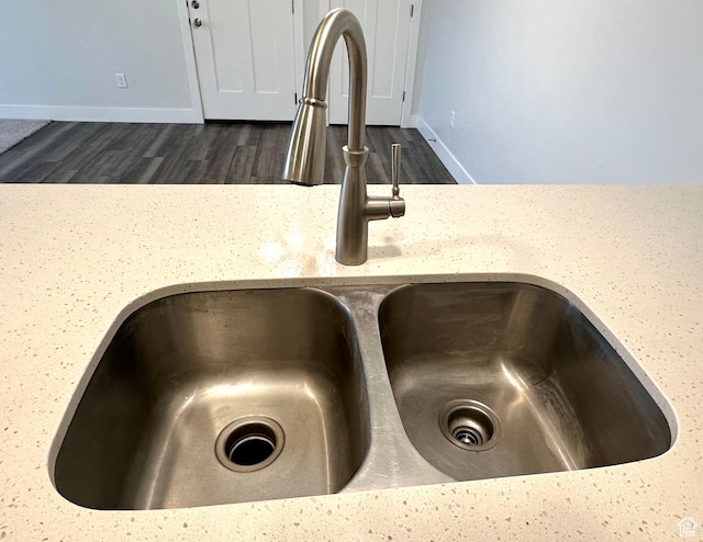 room details with dark wood-style floors, light stone countertops, a sink, and baseboards