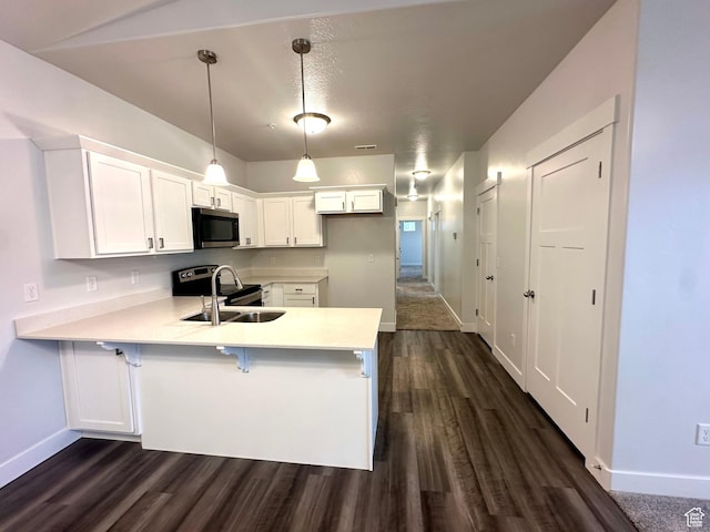 kitchen featuring appliances with stainless steel finishes, light countertops, a sink, baseboards, and a peninsula