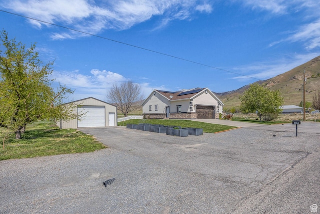 1563 Bryan Rd, Erda, UT 84074 - view of front facade with a mountain view, a detached garage, an outdoor structure, roof mounted solar panels, and a front yard
